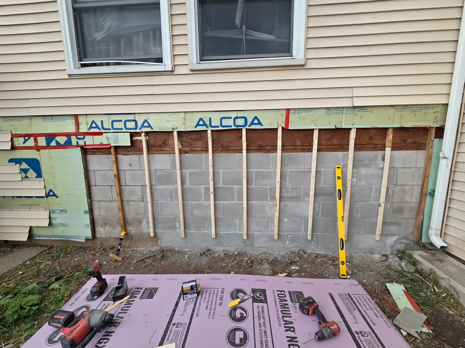 Exterior foundation wall with rigid foam insulation panels and vertical wood furring strips over concrete block