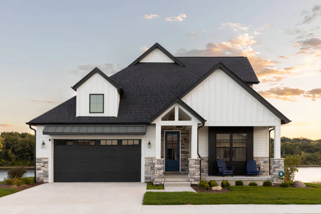 Modern farmhouse home with charcoal shingle roof, black trim, white board-and-batten siding, and stacked stone accents