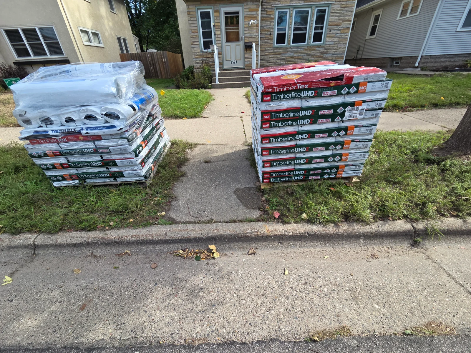 Pallets of GAF Timberline UHD and TimberTex shingles, synthetic underlayment rolls, and starter strip staged for roof installation